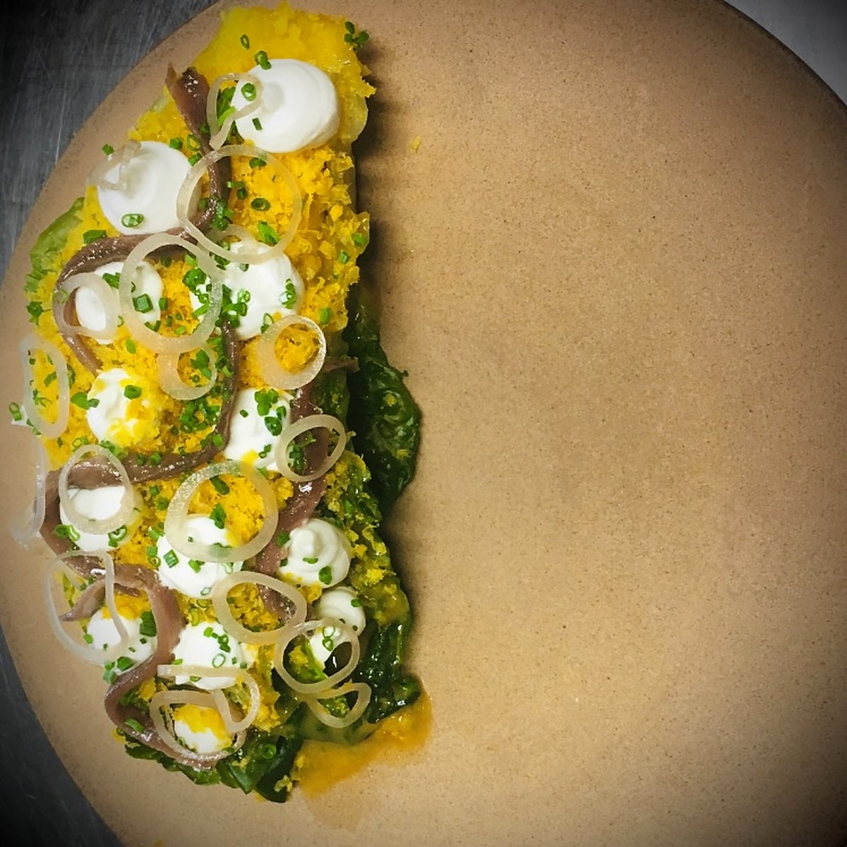 Anchovies, egg and greens on a stoneware plate
