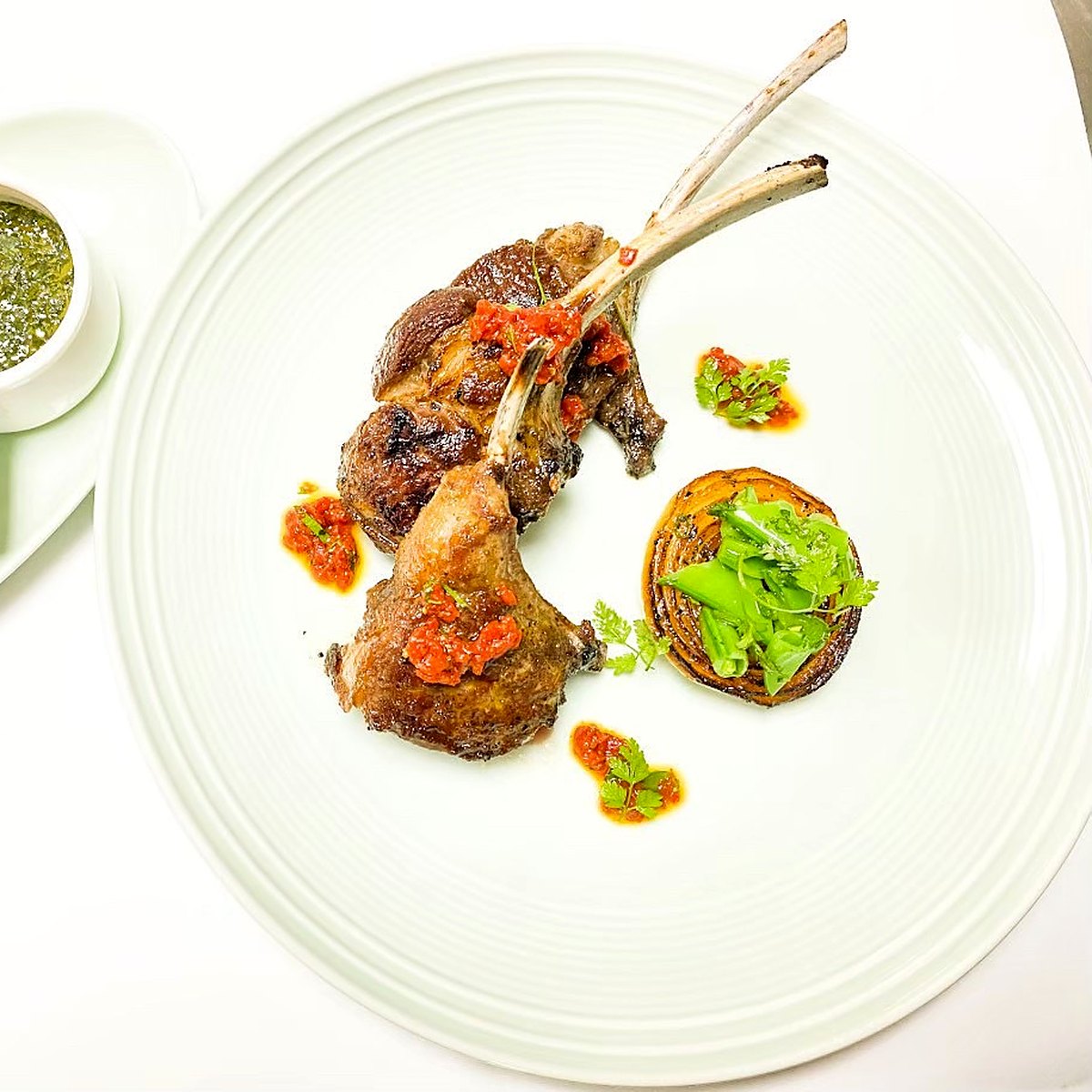 Lamb cutlets with romesco, charred onion and salsa verde