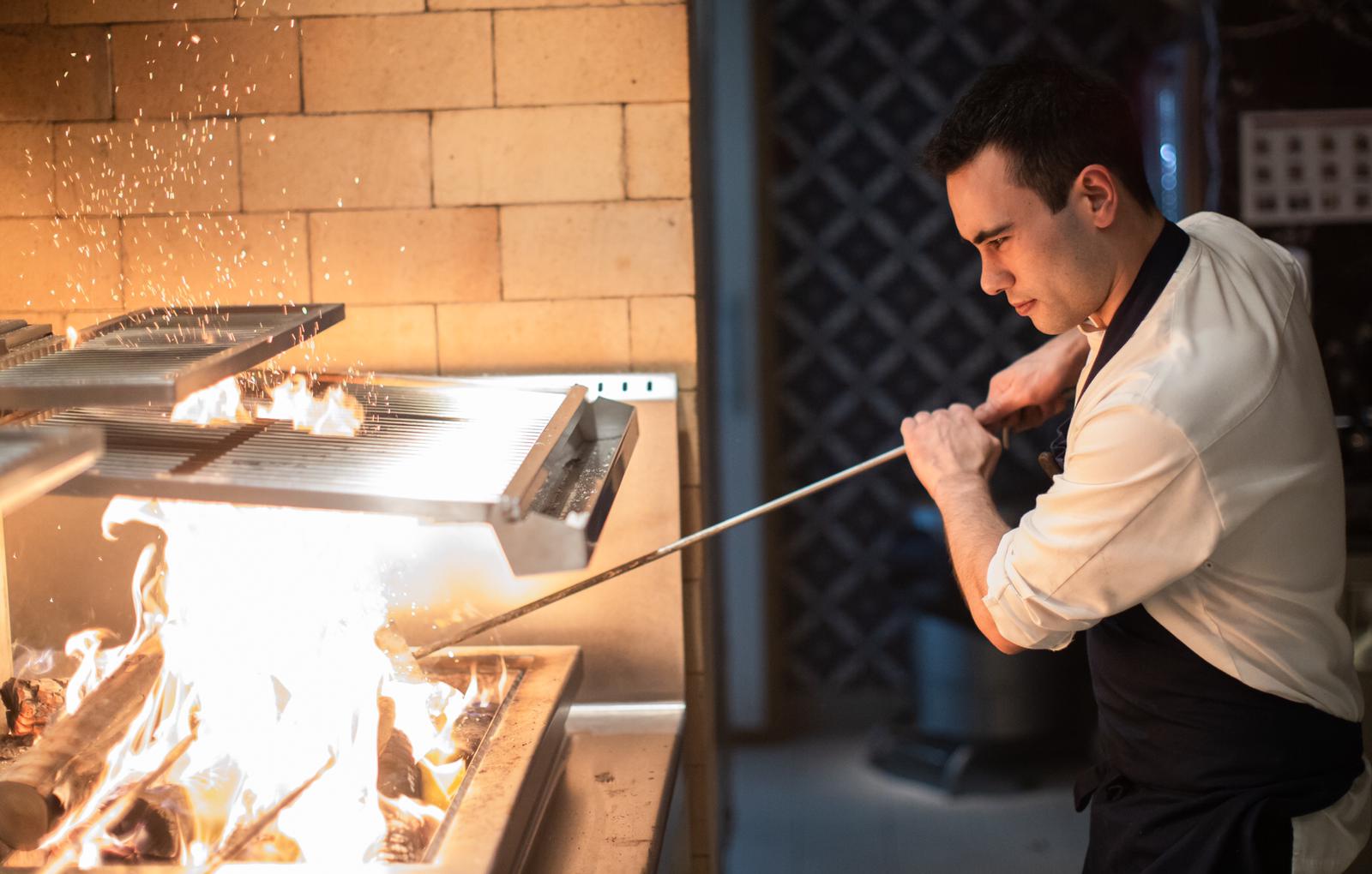 Working the open-fire grill, sparks flying
